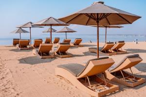 فندق أكانا البوتيكي في سانور: صف من الكراسي والمظلات على الشاطئ
