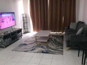 a living room with a tv and a couch and a table at CANA Homestay Petaling Jaya in Petaling Jaya