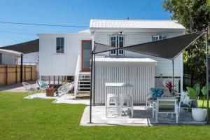 Casa blanca con mesa y sillas en el patio en Elegant 3-Bed 2-Bath Cottage: Classic Charm with a Modern Twist, en Townsville