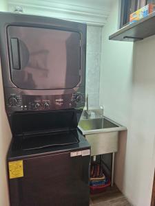 a microwave sitting on top of a refrigerator next to a sink at Loft Candelaria Pacaya in Antigua Guatemala