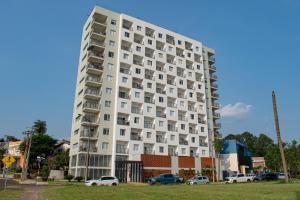 un edificio blanco alto con coches estacionados frente a él en Parana Playa 1103 en Encarnación