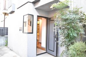 una casa de ladrillo blanco con una puerta negra en 恵比寿二丁目戸建, en Tokio
