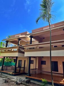 a house with a palm tree in front of it at BAVA Lalitha Retreat Center Varkala in Varkala