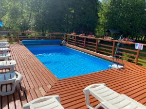 una piscina en una terraza de madera con sillas blancas en Кукулька міні-готель, en Slavske