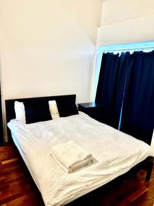 a bedroom with a white bed with blue curtains at Shoreditch apartment with lovely garden in London