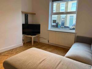 a living room with a couch and a flat screen tv at Lovely 3 Bedroom House South Norwood London in Norwood