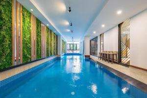 an indoor pool with blue water in a building with windows at Fansipan Da Nang Hotel in Da Nang