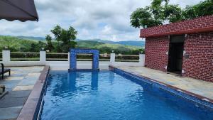 una piscina junto a un edificio de ladrillo con estructura azul en Skyview Villa Udaipur, en Udaipur