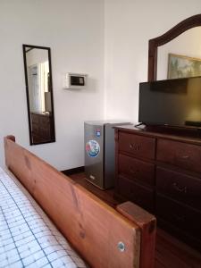 a bedroom with a tv and a dresser with a mirror at Chavenogue Hotel in San Juan