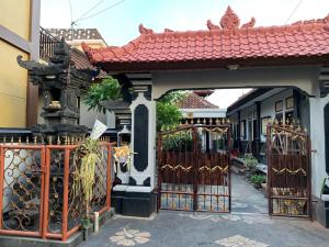 a gate to a house with a red roof at Tirtasuci House in Kuta