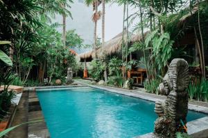 a pool in a resort with a statue in the middle at Way Ubud House in Ubud