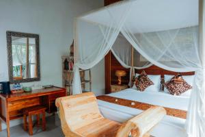 a bedroom with a canopy bed with a desk and a chair at Way Ubud House in Ubud
