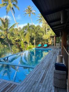a swimming pool on a deck with palm trees at Nanai Resort Salakphet in Ko Chang