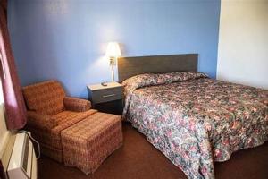 Habitación de hotel con cama y silla en American Inn, en Dermott