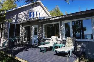 a screened in porch with two chairs and a table at Waterfront Cottage in Lion's Head in Stokes Bay