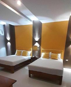 2 Betten in einem Zimmer mit gelben Wänden in der Unterkunft Maison De Gloria in Locsin