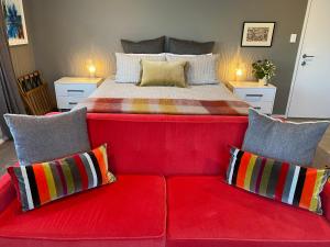 a red couch with pillows in front of a bed at Escape in New Plymouth
