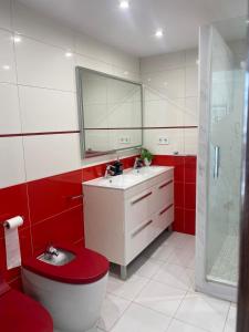 トレモリノスにあるAPARTAMENTO CON VISTAS AL MARの赤と白のバスルーム(トイレ、洗面台付)