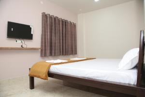 1 dormitorio con 1 cama y TV en la pared en Hotel Madhusudan Executive, en Kolhapur