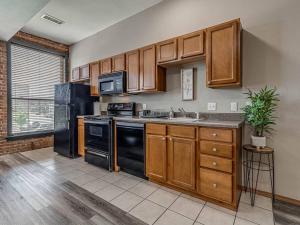 a kitchen with wooden cabinets and black appliances at Deluxe Studio in Historic Downtown Building! in Bartlesville