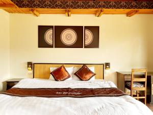 a bedroom with a white bed with two pillows at Vân Hồ Ecolodge in Mộc Châu