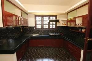 a large kitchen with black counter tops and a window at The Mallika Holidays in Mananthavady