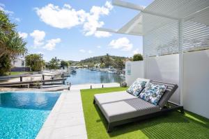 a patio with a couch and a view of the water at Callula Noosa, 9 Ravenwood Drive, Noosa Heads in Noosa Heads
