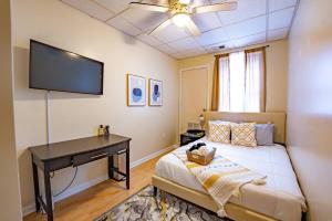 a bedroom with a bed with a desk and a flat screen tv at Brand New Cozy 2B & 1B I Downtown Wifi I Free Parking in Morgantown