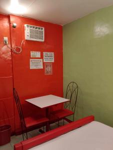 a table and chairs in a room with a red wall at WJV INN PALAWAN in Puerto Princesa City