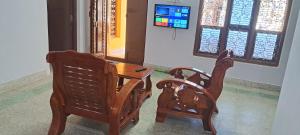 two wooden chairs and a table in front of a window at Major Madi Residency in Puducherry