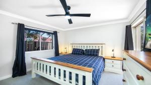 a bedroom with a bed and a ceiling fan at Summer By The Sea Umina Beach in Ettalong Beach