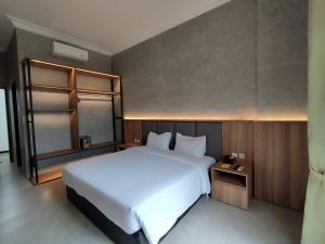 Un dormitorio con una gran cama blanca y una mesa en The Grand Palace Hotel Malang en Malang