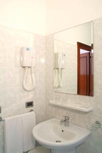 a white bathroom with a sink and a mirror at Hotel Alla Dolina in Sistiana