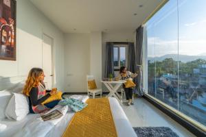 Dos mujeres sentadas en una habitación de hotel con ventana en ArtBuzz Dehradun en Dehradun