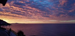un coucher de soleil sur l'océan avec un ciel nuageux dans l'établissement Relais Zio Vincenzo Casa Positano, à Positano