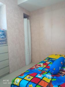 a bed with a colorful comforter in a bedroom at Apartement orchard Surabaya in Surabaya