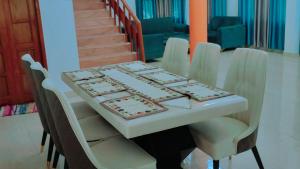 uma mesa com cadeiras brancas e uma mesa com pratos em The ROI Palace em Faridabad