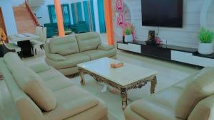 uma sala de estar com sofás, uma mesa e uma televisão em The ROI Palace em Faridabad