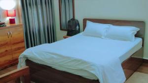 um quarto com uma cama branca e uma cabeceira em madeira em The ROI Palace em Faridabad