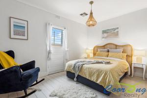 un dormitorio con una cama y una silla en Hyde Cottage, en Meningie