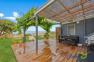 a wooden deck with a piano and a pergola at Hyde Cottage in Meningie