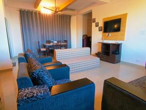 Sala de estar con 2 sofás azules y TV en Myst Asthetic Stays, en Kasauli