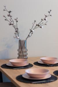 uma mesa com dois pratos e um vaso com flores em Modern One Bedroom Apartment with Parking in Łódź by Renters Prestige em Lódź