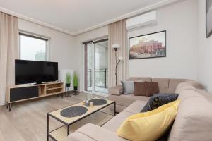 uma sala de estar com um sofá e uma televisão de ecrã plano em Modern One Bedroom Apartment with Parking in Łódź by Renters Prestige em Lódź