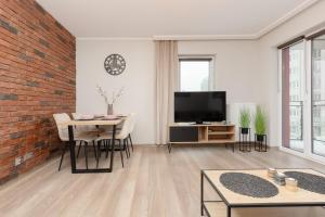 uma sala de estar com uma parede de tijolos e uma televisão em Modern One Bedroom Apartment with Parking in Łódź by Renters Prestige em Lódź