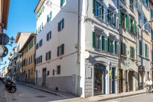 een wit gebouw met groene luiken op een straat bij Oltrarno Dreaming in Florence