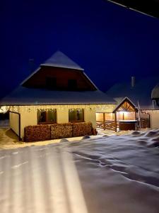 a house covered in snow at night with lights at Chata pod horou in Stará Lesná