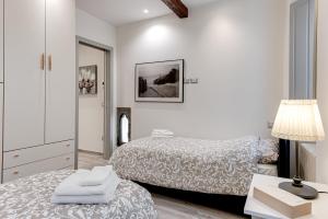 een witte slaapkamer met 2 bedden en een lamp bij Oltrarno Dreaming in Florence