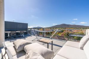 Un balcón con sofás blancos y una mesa y sillas. en 2BR Penthouse with Breathtaking View! - Hosted by CanStay, en Canberra