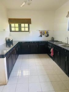 a kitchen with black cabinets and a white tile floor at Lagoon Paradise Beach Resort in Tangalle